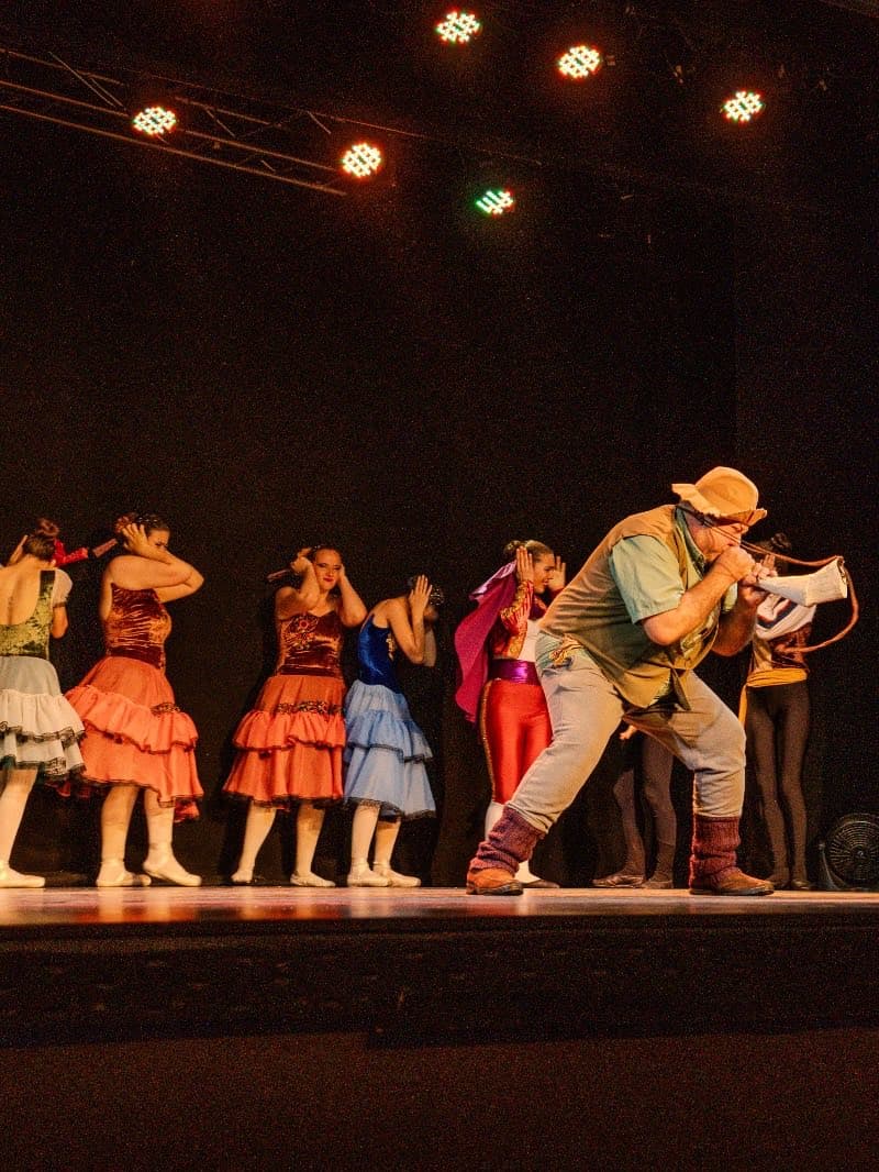 Escena de una función: un elenco en vestuario de carácter sobre el escenario