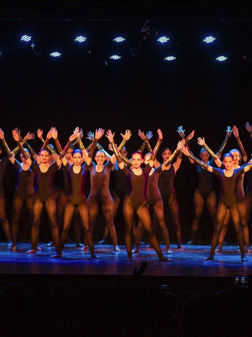 El elenco de jazz sobre el escenario, con los brazos en alto en el final de un número